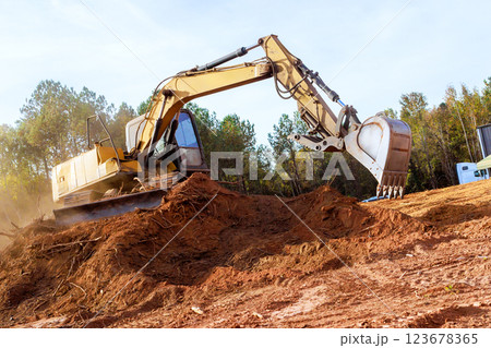 Large excavator works diligently, moving earth, debris at during construction site surrounded creating dusty atmosphere. 123678365