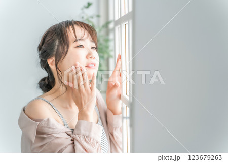 朝窓際に立つアジア人女性の美容イメージ(日光浴・スキンケア・紫外線) 朝窓際に立つアジア人女性の美容イメージ(日光浴・スキンケア・紫外線) 123679263