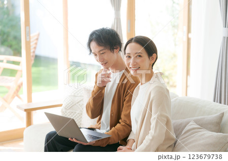 ソファに座ってパソコンを見る夫婦 123679738