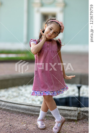 Young hispanic girl in pink dress posing outdoors by fountain Young hispanic girl in pink dress posing outdoors by fountain 123679759