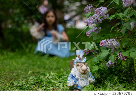 White rabbit figurine in garden with young caucasian girl in background White rabbit figurine in garden with young caucasian girl in background 123679795