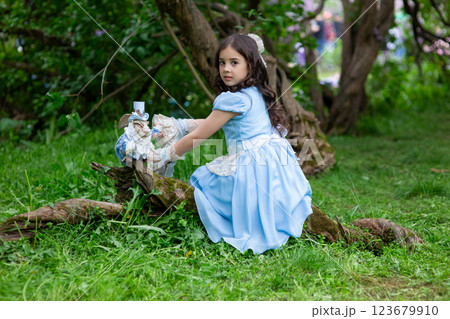 Pretty young girl in blue dress playing in forest with figurine Pretty young girl in blue dress playing in forest with figurine 123679910