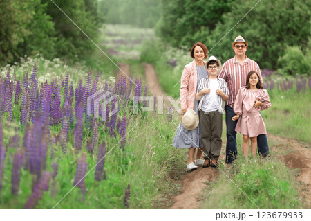 Family of four enjoying nature on a path amid purple flowers in a green forest 123679933
