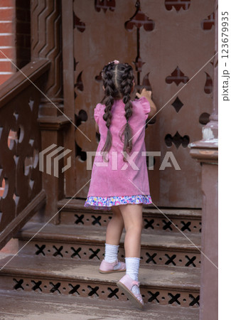 Little girl in a pink dress, opens an old carved wood door 123679935
