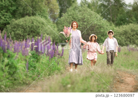 Caucasian young woman with children walking in lavender field holding flowers 123680097