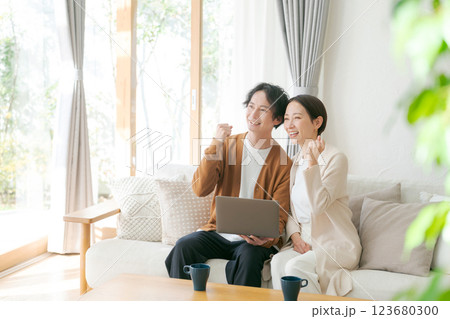 ソファに座ってパソコンを見る夫婦 123680300