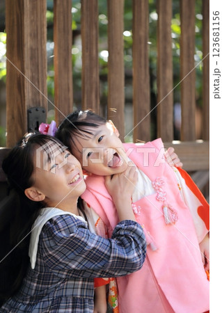 神社に七五三の参拝をする3歳の女の子と姉 123681156
