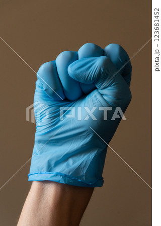 A person who is wearing a bright blue glove is making a wellrecognized peace  123681452