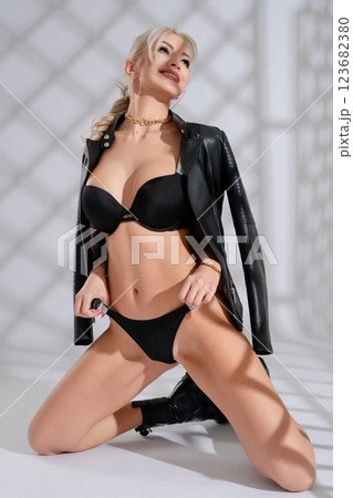Woman models stylish black lingerie with leather jacket in modern setting 123682380