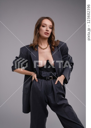 Stunning woman in corset and oversized blazer poses confidently in studio 123682396