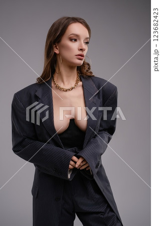 Sophisticated woman in a tailored suit showcasing lingerie in a studio 123682423