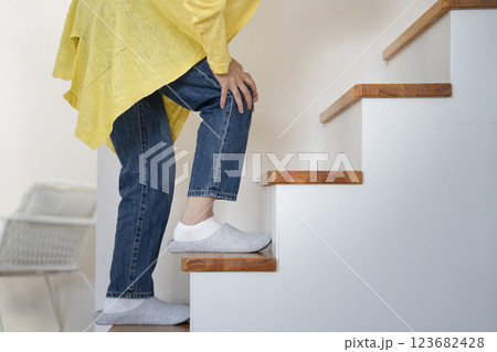 膝をおさえながら階段を登るシニア女性の下半身 膝をおさえながら階段を登るシニア女性の下半身 123682428