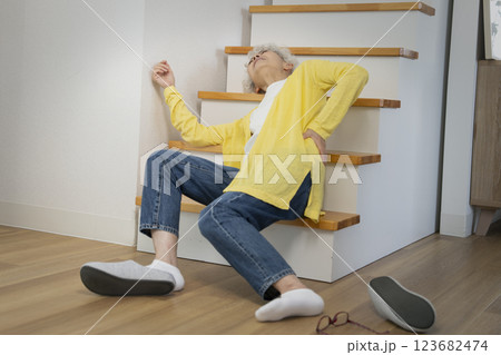 自宅の階段で転倒して腰をおさえるシニア女性 123682474