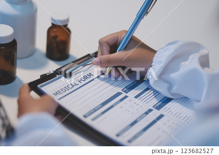 Doctor sitting at desk and writing a prescription for her patient 123682527
