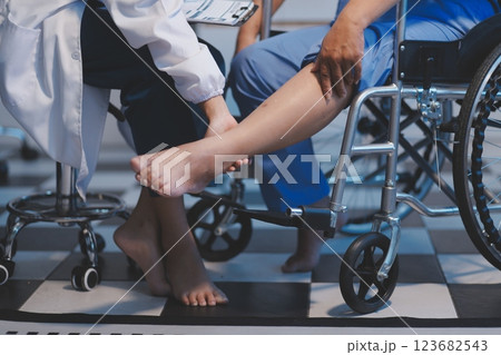 Asian young professional successful friendly female nurse in blue hospital uniform helping supporting physical therapy senior old pensioner unhealthy injury woman patient walking via four legs walker. Asian young professional successful friendly female nurse in blue hospital uniform helping supporting physical therapy senior old pensioner unhealthy injury woman patient walking via four legs walker. 123682543