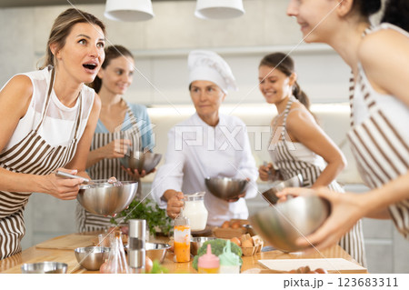 Young woman holding bowl and talking to other members Young woman holding bowl and talking to other members 123683311