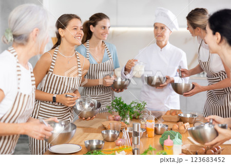 Young female visitor has nice conversation with person facing buddy vis-a-vis at culinary courses Young female visitor has nice conversation with person facing buddy vis-a-vis at culinary courses 123683452