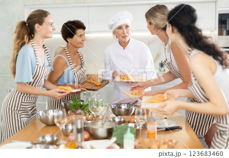 Mature female cook holding cutting board with raw chicken 123683460