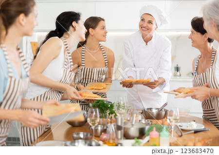 Young woman chef teaches how to cook chicken at master class Young woman chef teaches how to cook chicken at master class 123683470