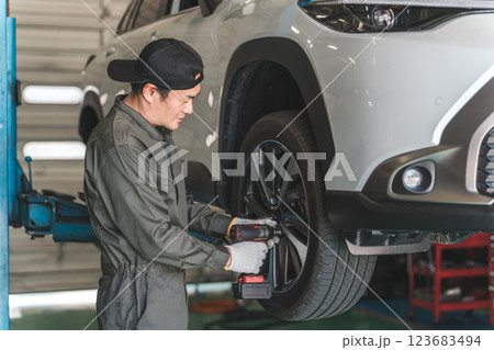 リフトアップした車のタイヤを脱着する整備士の男性（タイヤ交換） 123683494