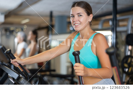 Portrait of sporty woman doing cardio workout on elliptical cross trainer at fitness center Portrait of sporty woman doing cardio workout on elliptical cross trainer at fitness center 123683526