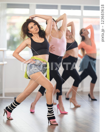 Female participants of project stand in row and perform dance in heels. Female participants of project stand in row and perform dance in heels. 123683618