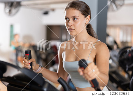 Sporty girl working out on elliptical machine in gym. Healthy active lifestyle concept 123683682
