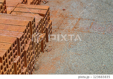 A few remaining rows of red mud bricks unloaded at the sidewalk and stacked for use in construction of a house. Concept of building materials, application technologies for construction of buildings A few remaining rows of red mud bricks unloaded at the sidewalk and stacked for use in construction of a house. Concept of building materials, application technologies for construction of buildings 123683835