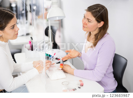 Client girl chooses a nail polish on a color palette Client girl chooses a nail polish on a color palette 123683987