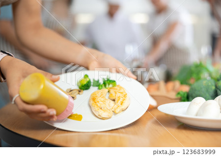 Womens hands decorate tender baked chicken fillet with sauce. Group lesson cooking courses. Close-up 123683999