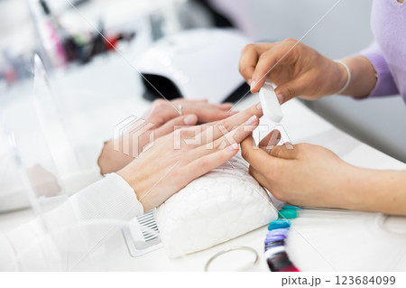 Woman hands, with which the manicure master files nails 123684099