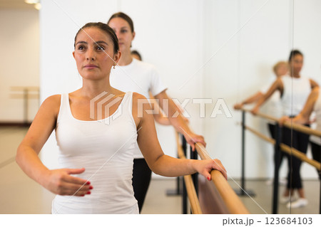 Latin american woman doing ballet stands holding a barre in a ballet stance 123684103