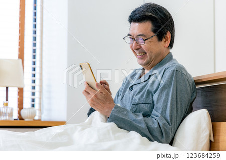 ベッドでスマホを使う中高年男性 眼鏡 ベッドでスマホを使う中高年男性 眼鏡 123684259