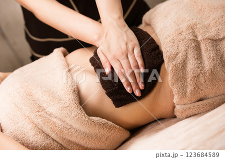 若いアジア人女性はタオルでおなかを拭かれています。 123684589