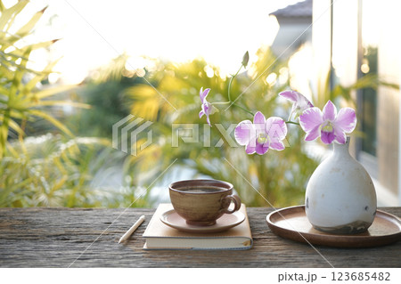 old notebook and vase of pink orchid flowers, cozy outdoor garden old notebook and vase of pink orchid flowers, cozy outdoor garden 123685482