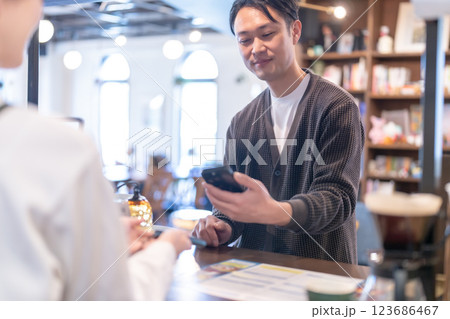 スマホ決済をする男性客と店の女性店員 スマホ決済をする男性客と店の女性店員 123686467