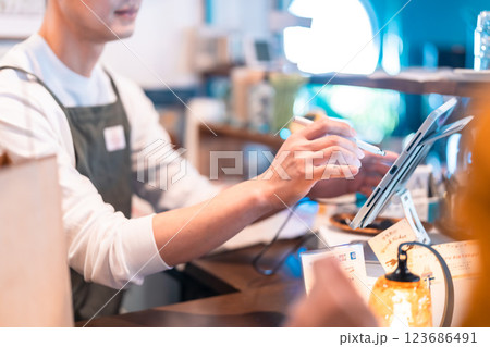 ペンでオーダーを取る男性店員　顔無し 123686491