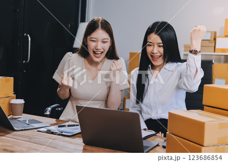 Startup SME small business entrepreneur of freelance Asian woman using a laptop with box Cheerful success Asian woman her hand lifts up online marketing packaging box and delivery SME idea concept 123686854