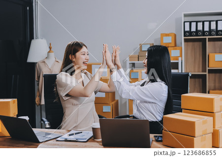 Startup SME small business entrepreneur of freelance Asian woman using a laptop with box Cheerful success Asian woman her hand lifts up online marketing packaging box and delivery SME idea concept Startup SME small business entrepreneur of freelance Asian woman using a laptop with box Cheerful success Asian woman her hand lifts up online marketing packaging box and delivery SME idea concept 123686855