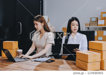 Startup SME small business entrepreneur of freelance Asian woman using a laptop with box Cheerful success Asian woman her hand lifts up online marketing packaging box and delivery SME idea concept 123686902