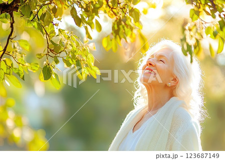 Elderly woman enjoying serene moment under sunlight surrounded by nature in a beautiful park 123687149
