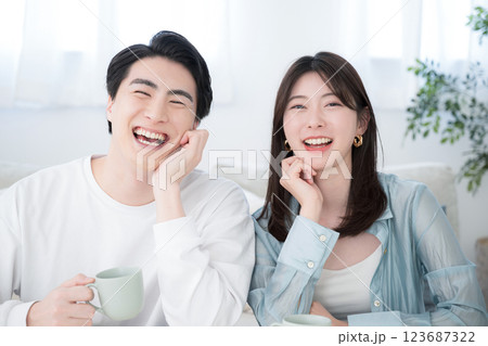 リビングで笑顔の若いカップル　カメラ目線　大笑いで幸せそうなイメージ	 123687322