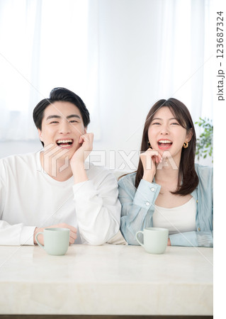 リビングで笑顔の若いカップル カメラ目線 大笑いで幸せそうなイメージ リビングで笑顔の若いカップル カメラ目線 大笑いで幸せそうなイメージ 123687324