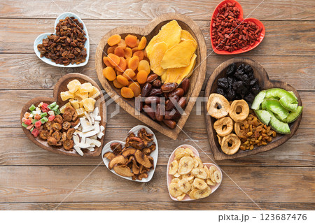 Healthy sweet dried fruits and berries in wooden heart shaped plates on wooden background.Top view. 123687476