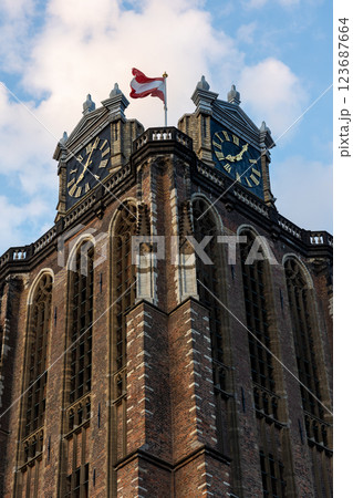 A majestic Gothic church under a dramatic cloudy sky. The intricate brickwork, towering windows, and clock tower reflect its historic architecture and timeless grandeur. 123687664