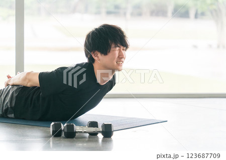 上体反らしをする若い男性（背筋・筋トレ・バックエクステンション・自重トレーニング） 123687709