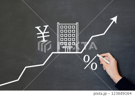 マンションの価格や住宅ローン金利が上がるイメージを黒板に描く人物の手元 123689164