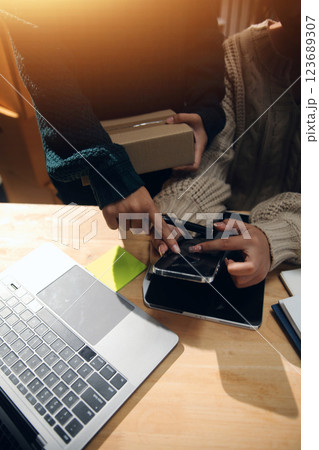 Startup small business SME, Entrepreneur owner African woman using smartphone or tablet taking receive and checking online purchase shopping order to preparing pack product box. 123689307