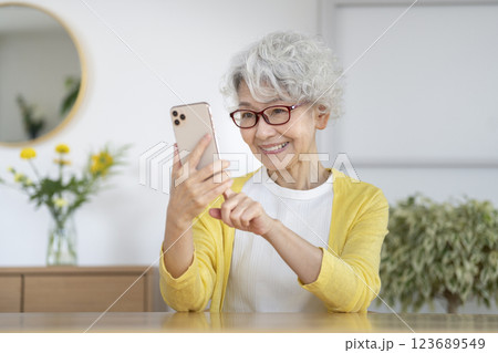 スマートフォンを持ったメガネをかけたシニア女性 スマートフォンを持ったメガネをかけたシニア女性 123689549