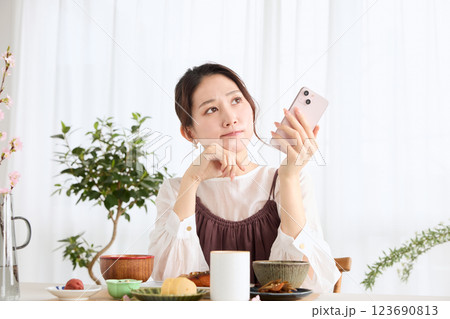 朝食にスマートフォンを見る女性 朝食にスマートフォンを見る女性 123690813